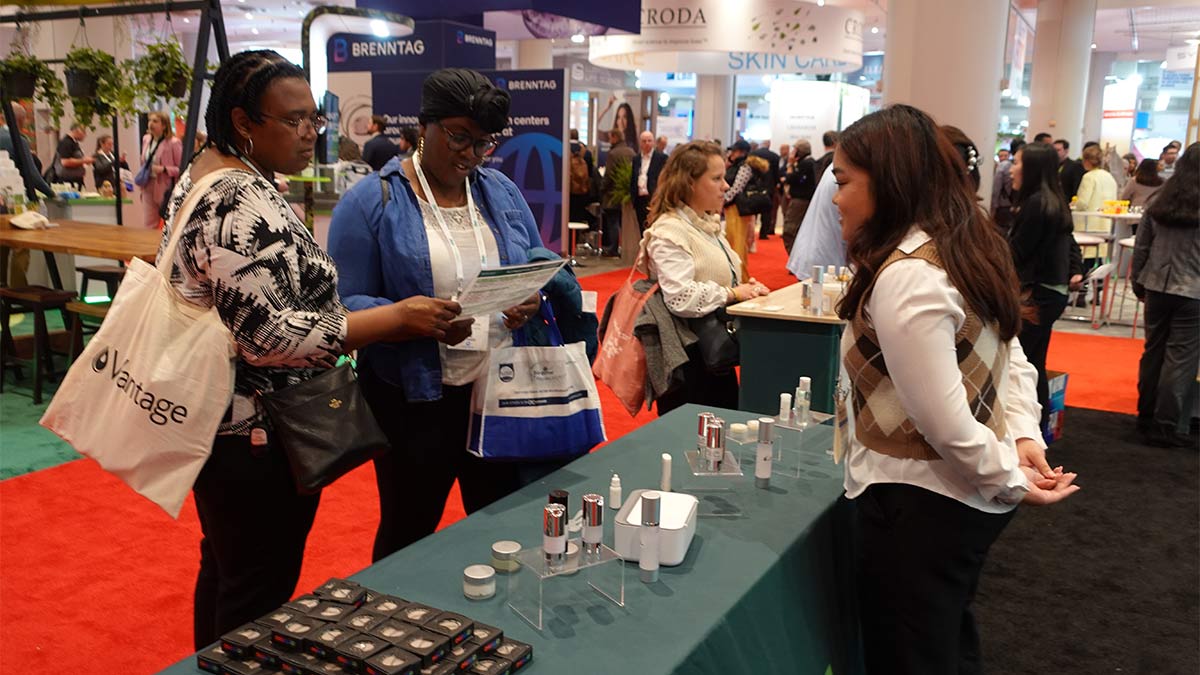Two conference attendees talk with an Applechem booth attendant.
